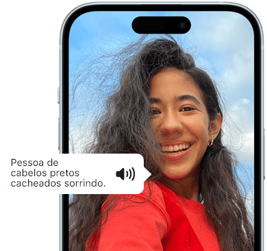 iPhone 15 mostrando um texto anunciado pelo Voiceover que descreve uma foto como: pessoa de cabelos pretos cacheados sorrindo.