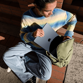 Imagem de uma pessoa guardando um MacBook Air de 15 polegadas na mochila